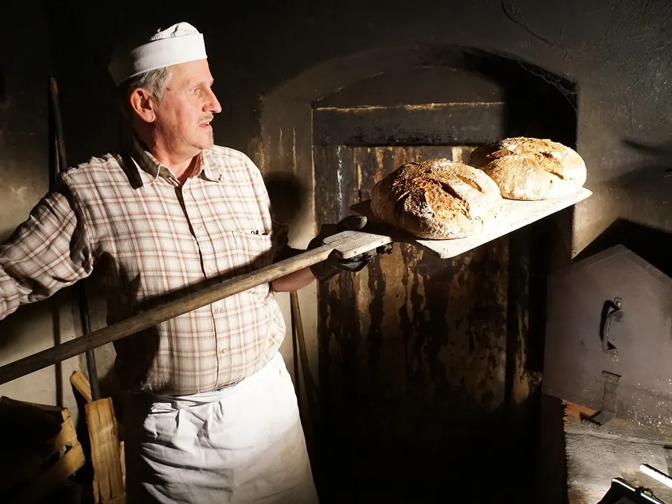 The baker taking bread out of the oven
